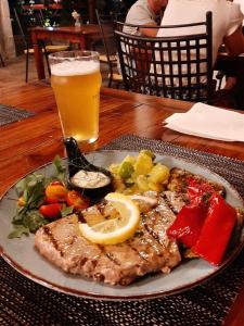 a plate of food with meat and vegetables and a glass of beer at White Cloud Apartments in Korčula