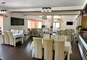 ein Esszimmer mit weißen Tischen und weißen Stühlen in der Unterkunft Aranykakas étterem és panzió in Sîndominic