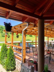 pérgola de madera con mesas y sillas en el patio en Aranykakas étterem és panzió, en Sîndominic