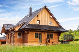 ein Holzhaus mit schwarzem Dach in der Unterkunft Chata Hrozenka WELLNESS in Nový Hrozenkov