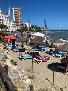 Sitio de CalahondaにあるPueblo Los Olivosの椅子とパラソルに座る人々のいるビーチ