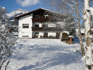 una casa con un patio cubierto de nieve delante de ella en Ferienwohnungen Kathrein, en Reutte