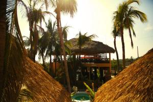 un complejo con palmeras y un edificio con piscina en One Love Hostal Puerto Escondido en Puerto Escondido