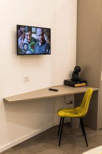 uma secretária com uma cadeira amarela e uma televisão na parede em Morpheus Rooms em Nápoles