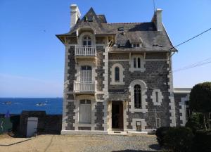 an old stone building with the ocean in the background at La Perle Marine in Dinard