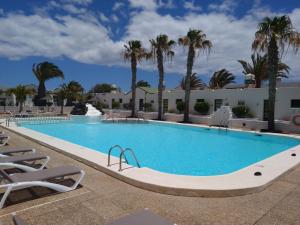 duży basen z palmami w tle w obiekcie Apartment duplex -The Sunny Hut - swimming pool - Free Wifi & AC- Residence Las Marinas w Puerto del Carmen