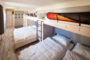 a room with three bunk beds and a surfboard on top at Oberstdorf Hostel in Oberstdorf