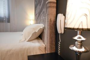 a hotel room with a phone next to a bed at Hôtel Les Muses in Annecy