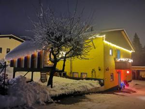 une personne debout devant une maison jaune éclairée dans l'établissement Ferienwohnung im Landhausstil, à Oberreute