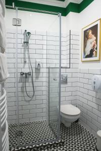 a white bathroom with a shower and a toilet at Hotel Tókert Szálloda és Étterem in Lillafüred