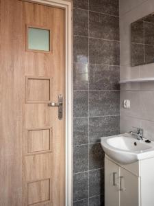 een badkamer met een houten deur en een wastafel bij Ośrodek wypoczynkowy - Wczasy w Cichowie in Cichowo