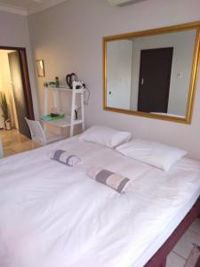 Xenia Bed & Breakfast في ويندهوك: سرير أبيض كبير مع مرآة كبيرة على الحائط