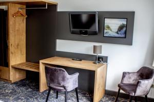 a room with two chairs and a desk and a tv at Landhaus Oltmanns in Moormerland