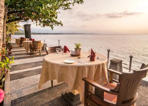 einen Tisch mit Stühlen und einen Tisch mit Blick auf das Wasser in der Unterkunft Nugraha Lovina Seaview Resort & Spa in Lovina