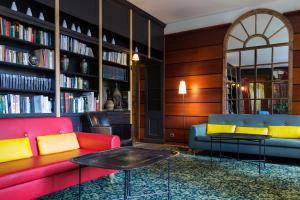 een bibliotheek met rode en blauwe banken en een tafel bij Hôtel Relais Monceau in Parijs