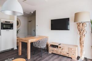 ein Wohnzimmer mit einem Tisch und einem TV an der Wand in der Unterkunft Dünenquartier Apartment 12 in Zingst