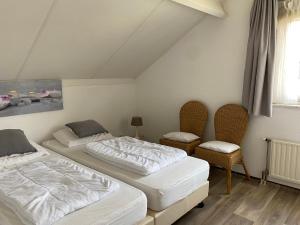 1 Schlafzimmer mit 2 Betten und 2 Stühlen in der Unterkunft Hello Zeeland - Vakantiehuis Schelde 254 in Breskens