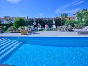 a blue swimming pool with people sitting in chairs and tables at Dolce Vita Boutique Hotel in Porto Cervo