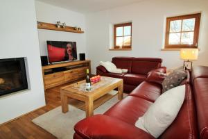 ein Wohnzimmer mit roten Ledermöbeln und einem Flachbild-TV in der Unterkunft Apartment Jochberg by Apartment Managers in Jochberg