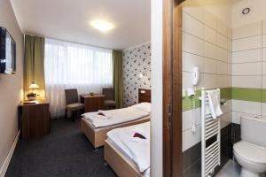 a hotel room with two beds and a bathroom at Arkada Hotel in Bučovice +37 photos