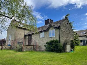 an old brick house on a green lawn at Nethercote Cottage, Seven Springs Cottages in Cheltenham