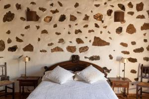 a bedroom with a bed and a wall with rocks at Joya del Jable in Tao