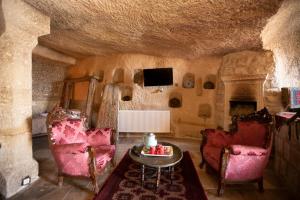 Una sala de estar con sillas, una mesa y un televisor. en Antique Terrace Cave Suites, en Göreme