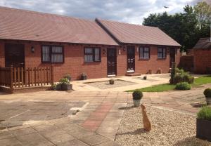 a brick house with a cat sitting in front of it at Newent Golf Club and Lodges in Newent