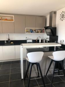 a kitchen with white counters and white stools at Annecy centre, Appartement en attique avec vue panoramique in Annecy