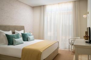 a bedroom with a bed with blue pillows and a window at Monte Santo Resort in Carvoeiro