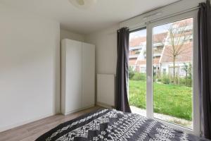 a bedroom with a bed and a large window at Spacious 3-rooms with garden close to Lille in Lille