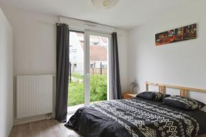 a bedroom with a bed and a large window at Spacious 3-rooms with garden close to Lille in Lille