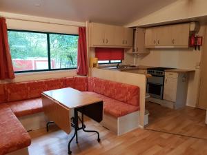 a living room with a red couch and a kitchen at Camping Au Bois Dormant in Chauffour-sur-Vell
