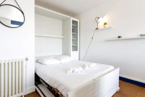 a white bedroom with a bed and a mirror at Studio Thalmar - Welkeys in Biarritz +4 photos