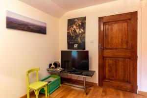 um quarto com uma televisão, uma mesa e uma porta em La Maison de Caroline em Colombiès