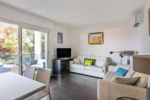 a living room with a white couch and a tv at Breathtaking 2br with terrace close to beaches in Antibes