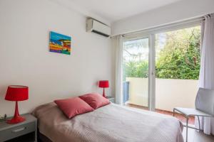 a bedroom with a bed and a large window at Appartement Oasis - Welkeys in Antibes
