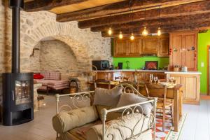 a living room with a fireplace and a kitchen with green walls at La Maison de Caroline in Colombiès