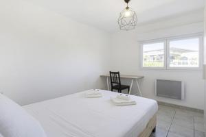 um quarto branco com uma cama, uma secretária e uma janela em Superb triplex with panoramic terrace - Bayonne - Welkeys em Baiona