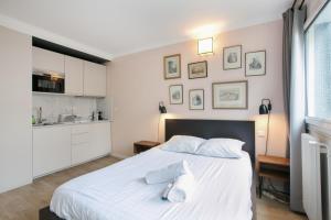 1 Schlafzimmer mit einem großen weißen Bett und einer Küche in der Unterkunft Cozy studio 10 min from Eiffel Tower Invalides Beaugrenelle in Paris