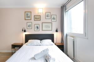 1 dormitorio con 1 cama con sábanas blancas y ventana en Cozy studio 10 min from Eiffel Tower Invalides Beaugrenelle, en París