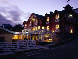 a large wooden house with lights on at Hostería Patagonia Jarke in Ushuaia