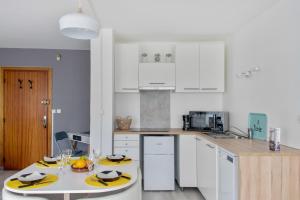 a kitchen with white cabinets and a table with yellow chargers at Nice studio with balcony and parking in Villeurbanne near Lyon - Welkeys in Villeurbanne