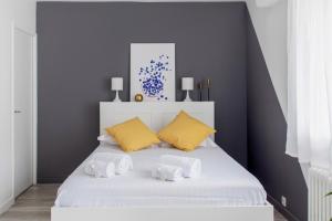 - une chambre avec un lit blanc et des oreillers jaunes dans l'établissement Nice studio with balcony and parking in Villeurbanne near Lyon - Welkeys, à Villeurbanne