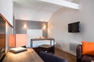 ein Wohnzimmer mit einem Tisch und einem TV an der Wand in der Unterkunft Beffroi - Cosy studio close to Vieux Lille - Welkeys in Lille