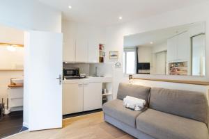 a living room with a couch and a kitchen at Cosy studio in Paris close to Grands Boulevards and Bourse - Welkeys in Paris