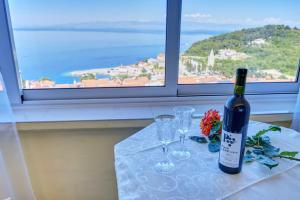 a bottle of wine sitting on a table with glasses at Apartment Goga - Seaview & Parking in Mali Lošinj