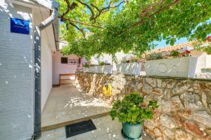 a stone wall with potted plants next to a building at Apartment Goga in Mali Lošinj