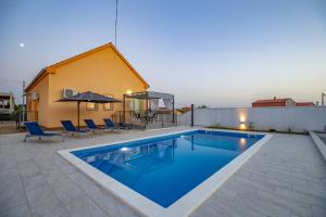una piscina en un patio con sillas y una casa en Villa Family and Friends private heated pool with jacuzzi, en Zadar