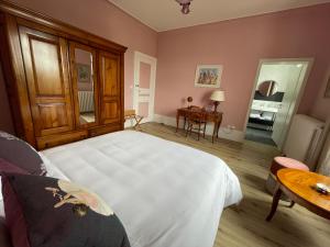 um quarto com uma cama branca e uma mesa em La Maison Bleue « La Charade » em Thaon-les-Vosges